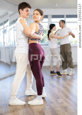 Dance studio - students in casual clothes learn to dance tango 129581127