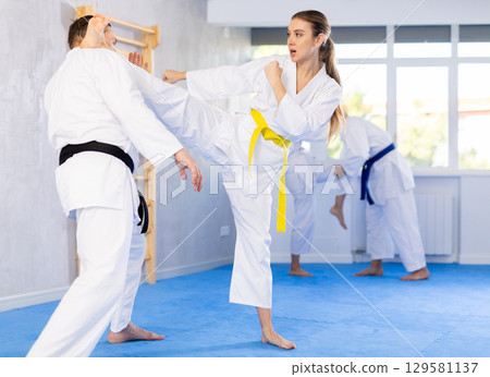Young girl in kimono applying kicks on her partner Young girl in kimono applying kicks on her partner 129581137