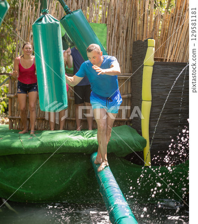 Man walking through water obstacle course in amusement park Man walking through water obstacle course in amusement park 129581181