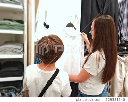 beautiful woman and a boy are choosing clothes in a boutique store. School uniform. Back to school 129581340