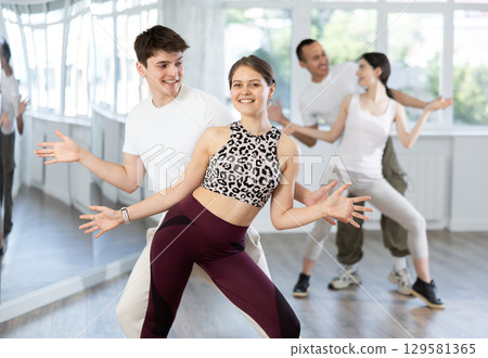 Cheerful young couple practicing playful Charleston in dance studio 129581365