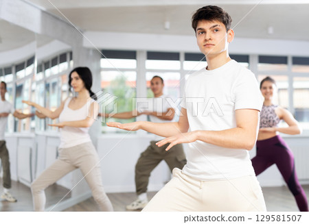 Enthusiastic Hispanic guy energizing group during fitness class 129581507