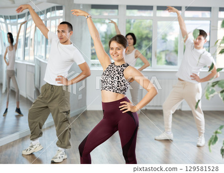 Smiling young people practicing vigorous lindy hop movements in dance class 129581528