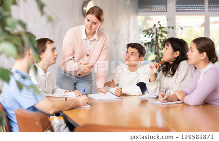 Young female professor explaining subject to group of students Young female professor explaining subject to group of students 129581871