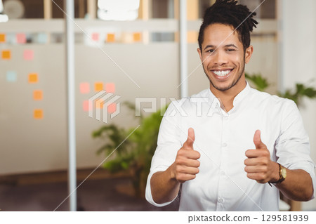 African American worker giving thumbs up by glass partition with sticky notes in office, copy space 129581939