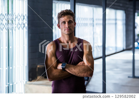 Muscular man standing with arms crossed in gym wearing smartwatch near weight rack, grid windows Muscular man standing with arms crossed in gym wearing smartwatch near weight rack, grid windows 129582002