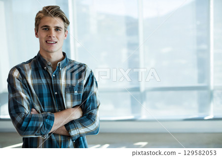 Man in his thirties wearing shirt standing inside office by floor-to-ceiling windows, copy space 129582053