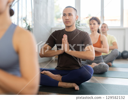 Male lover of active lifestyle on yoga mat perform doing lotus position, padmasana in gym 129582132