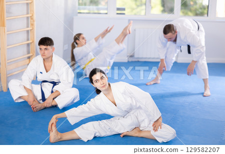 Sports team doing muscle stretching before karate or judo training 129582207