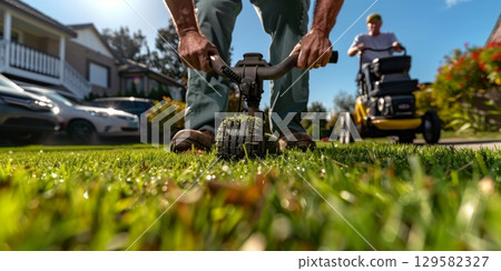 Gardener aerating lawn for healthy growth in residential area 129582327