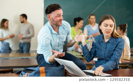Dissatisfied female student showing stop gesture to annoying male friend at auditorium of university during break between lectures 129582358