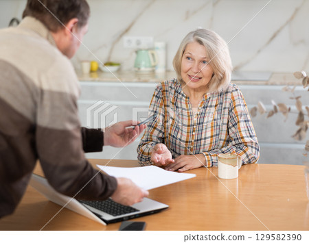 Male financial agent tells an elderly woman terms of microloan. Offers to sign documents 129582390