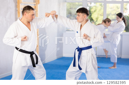 Athletes sparring during karate classes in gym Athletes sparring during karate classes in gym 129582395