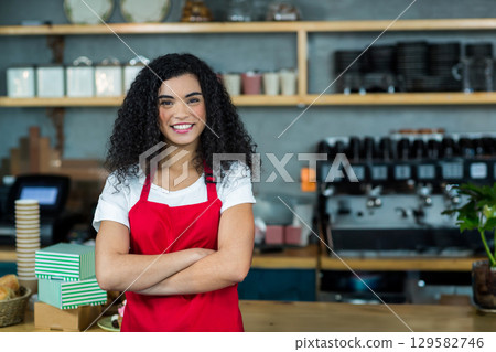 African American woman in red apron operating espresso machine behind counter in coffee shop African American woman in red apron operating espresso machine behind counter in coffee shop 129582746