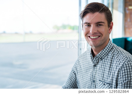Man sitting in lounge facing camera on upholstered chair near glass windows, copy space Man sitting in lounge facing camera on upholstered chair near glass windows, copy space 129582864