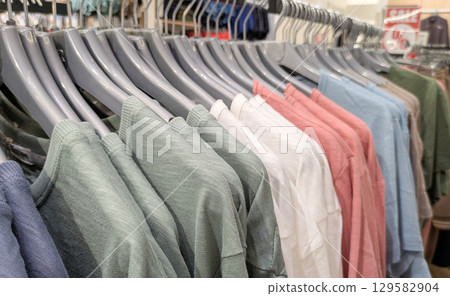 Clothes rack in the store displays various cotton T-shirts in different colors. Ideal for summer fashion, retail and shopping concepts Clothes rack in the store displays various cotton T-shirts in different colors. Ideal for summer fashion, retail and shopping concepts 129582904