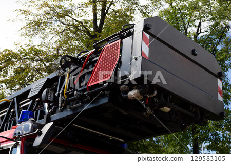Folded ladder on the roof of fire vehicle. Long telescopic ladder for unfolding of accident. Rescuing people from high floors, firefighting in skyscraper concept. Fire equipment Folded ladder on the roof of fire vehicle. Long telescopic ladder for unfolding of accident. Rescuing people from high floors, firefighting in skyscraper concept. Fire equipment 129583105