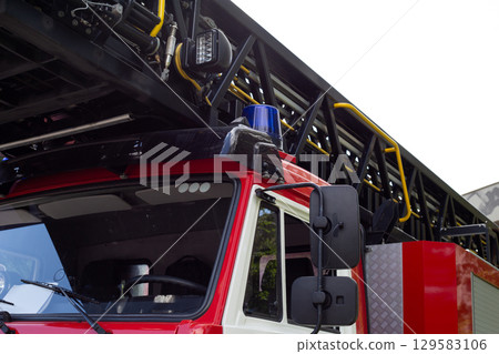 Fire engine cabin with long folding ladder with blue siren accent for visibility of rescue services. Special ladder on roof of fire safety vehicle for rescuing people from height Fire engine cabin with long folding ladder with blue siren accent for visibility of rescue services. Special ladder on roof of fire safety vehicle for rescuing people from height 129583106