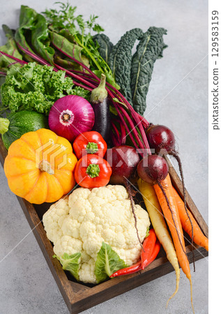 Fresh organic vegetables arranged in a wooden crate, showcasing vibrant colors and textures, perfect for healthy cooking and meal preparation 129583159