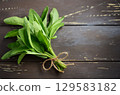 Freshly harvested sage leaves tied with twine on rustic wooden surface, showcasing vibrant green color and natural texture for culinary use 129583182