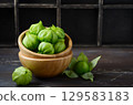Fresh green tomatillos arranged in a wooden bowl on a rustic table, showcasing vibrant colors and natural textures for culinary inspiration 129583183