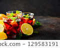 Sangria cocktail in clear glasses with fresh fruit and mint leaves, vibrant colors creating a refreshing summer drink atmosphere 129583191