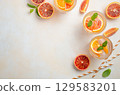 Refreshing citrus drinks with blood orange slices and mint leaves, arranged on a light background, perfect for summer gatherings and celebrations 129583201
