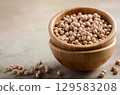 Wooden bowls filled with dried chickpeas on a textured surface, showcasing natural ingredients and healthy cooking options for culinary enthusiasts 129583208