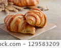 Freshly baked golden croissants resting on parchment paper, showcasing flaky layers and rich texture, perfect for breakfast or pastry lovers 129583209