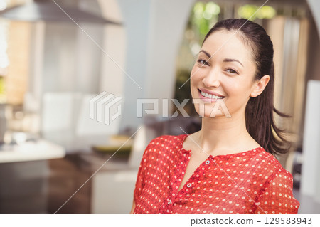 Asian woman standing smiling in kitchen wearing red polka-dot blouse with fruit bowl, copy space Asian woman standing smiling in kitchen wearing red polka-dot blouse with fruit bowl, copy space 129583943
