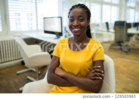 African American woman sitting in white swivel chair at modern office desk by computer monitor 129583983