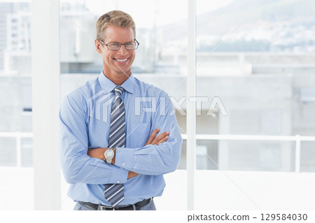 Adult male standing arms crossed before office windows wearing eyeglasses striped tie wristwatch 129584030