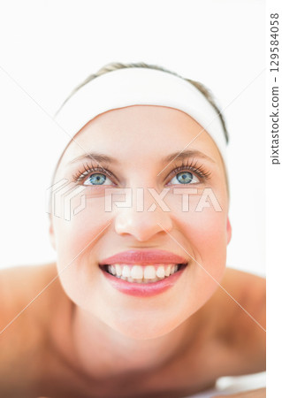 Woman in her twenties smiling broadly and gazing upward in bright studio wearing white headband Woman in her twenties smiling broadly and gazing upward in bright studio wearing white headband 129584058