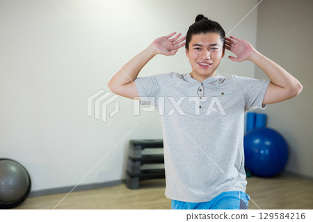 Chinese woman in sportswear performing core exercise kneeling in studio with stability balls Chinese woman in sportswear performing core exercise kneeling in studio with stability balls 129584216