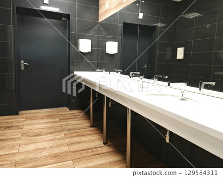 interior of toilet is in black shades. black and white. mirror, sink, toilet. black, public toilet 129584311