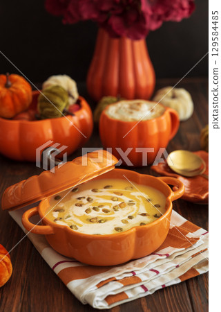 Autumnal lunch with pumpkin soup in a pumpkin-shaped bowl, pumpkin latte, croutons and festive decor on dark wooden table Autumnal lunch with pumpkin soup in a pumpkin-shaped bowl, pumpkin latte, croutons and festive decor on dark wooden table 129584485