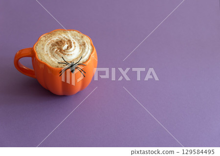 Halloween themed flat lay with a pumpkin latte and spiderwebs on a purple background. Halloween themed flat lay with a pumpkin latte and spiderwebs on a purple background. 129584495