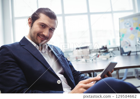 Man in business attire checking smartphone sitting at office desk by whiteboard notes, copy space Man in business attire checking smartphone sitting at office desk by whiteboard notes, copy space 129584662