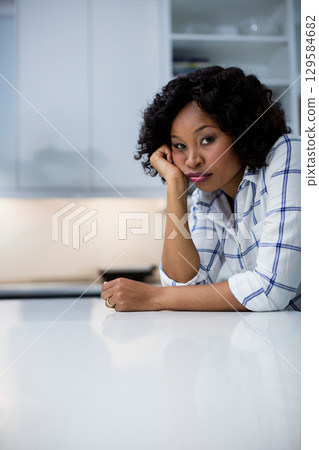 African American woman leaning on kitchen counter gazing while showing ring on hand, copy space 129584682