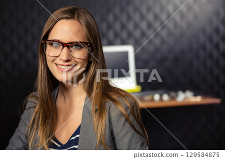 Woman professional wearing eyeglasses displaying metal parts next to laptop at desk, copy space Woman professional wearing eyeglasses displaying metal parts next to laptop at desk, copy space 129584875