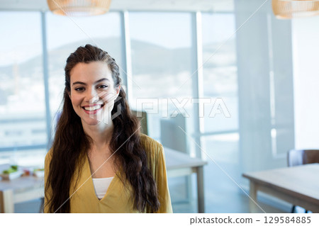 Woman standing by computer monitor and table in bright open-plan office overlooking water and hills Woman standing by computer monitor and table in bright open-plan office overlooking water and hills 129584885