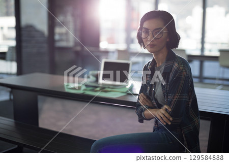 Asian woman in her twenties working on laptop amid papers at communal workspace bench, copy space 129584888