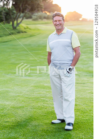 Senior African American man standing on golf fairway at sunset wearing golf glove, sweater vest Senior African American man standing on golf fairway at sunset wearing golf glove, sweater vest 129584918