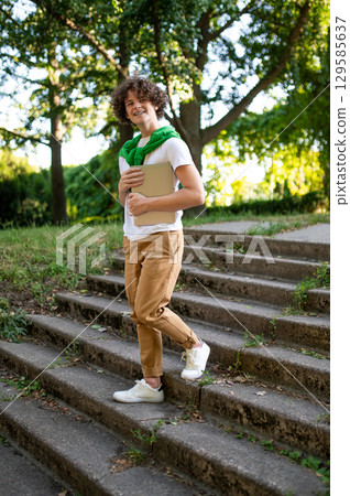 Curly-haired teen on the steps in the park looking contented 129585637