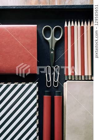 Organized workspace with stationery items on a black background ready for creative tasks 129585651