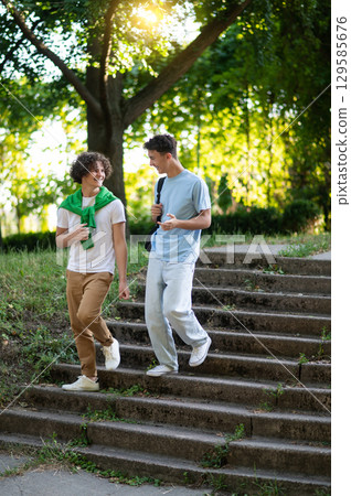 Two teens walking in the park after school and looking contented 129585676