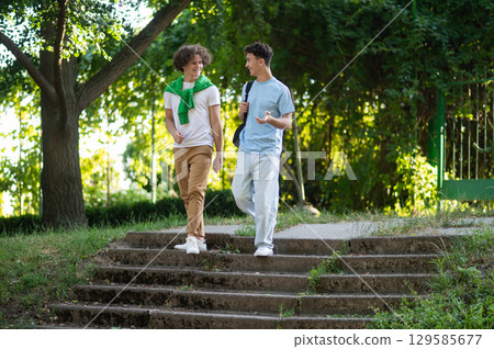 Two teens walking in the park after school and looking contented Two teens walking in the park after school and looking contented 129585677