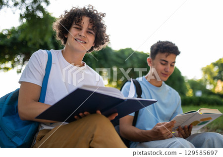 Two teens sitting in the park and studying together 129585697