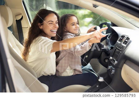 Young woman and her daughter sitting in the car and looking joyful 129585793