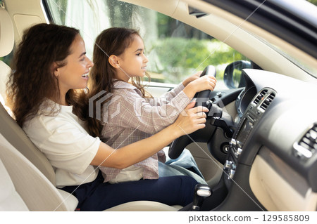 Young woman and her daughter sitting in the car and looking joyful 129585809